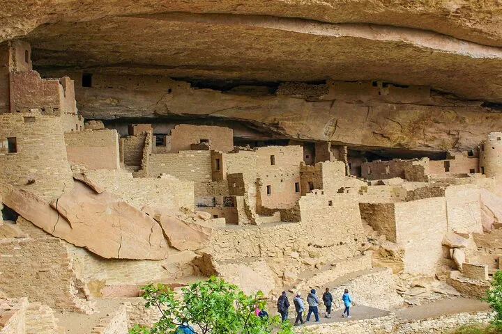 Tourists walking along a path below the massive Cliff Palace ruins.